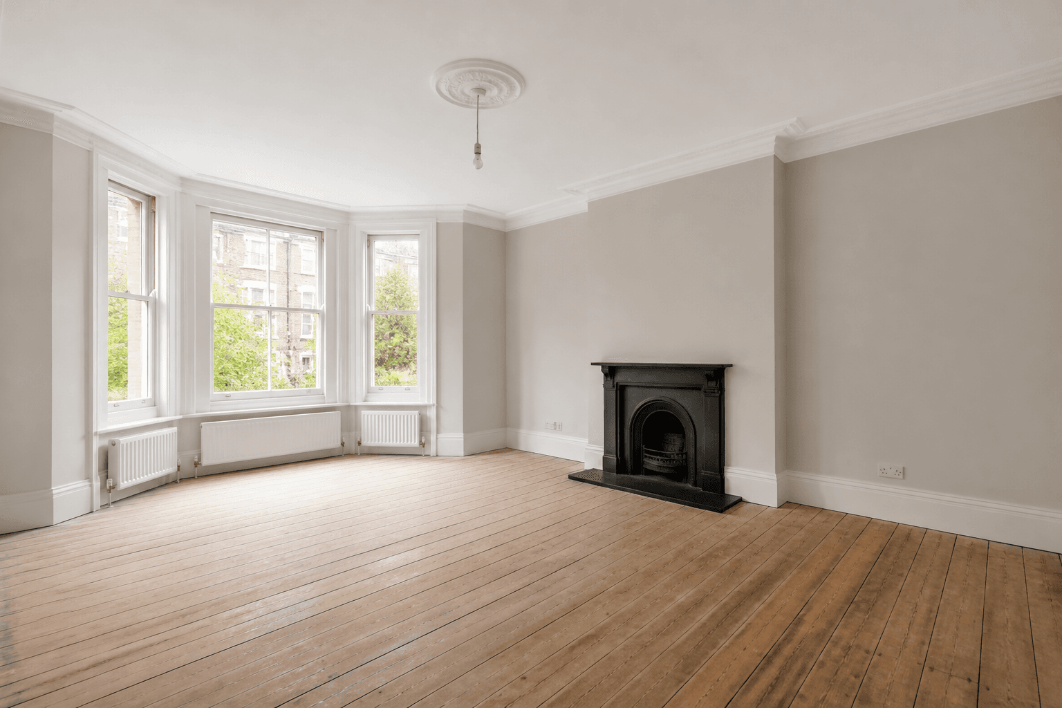 Bright empty UK living room photographed for a property listing before virtual staging, with large windows and clean neutral walls